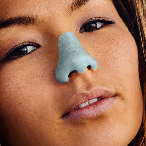 A woman wearing NÖZ’s blue reef safe colored sunblock stick.